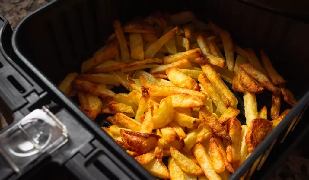 Golden crispy french fries in an air fryer basket.