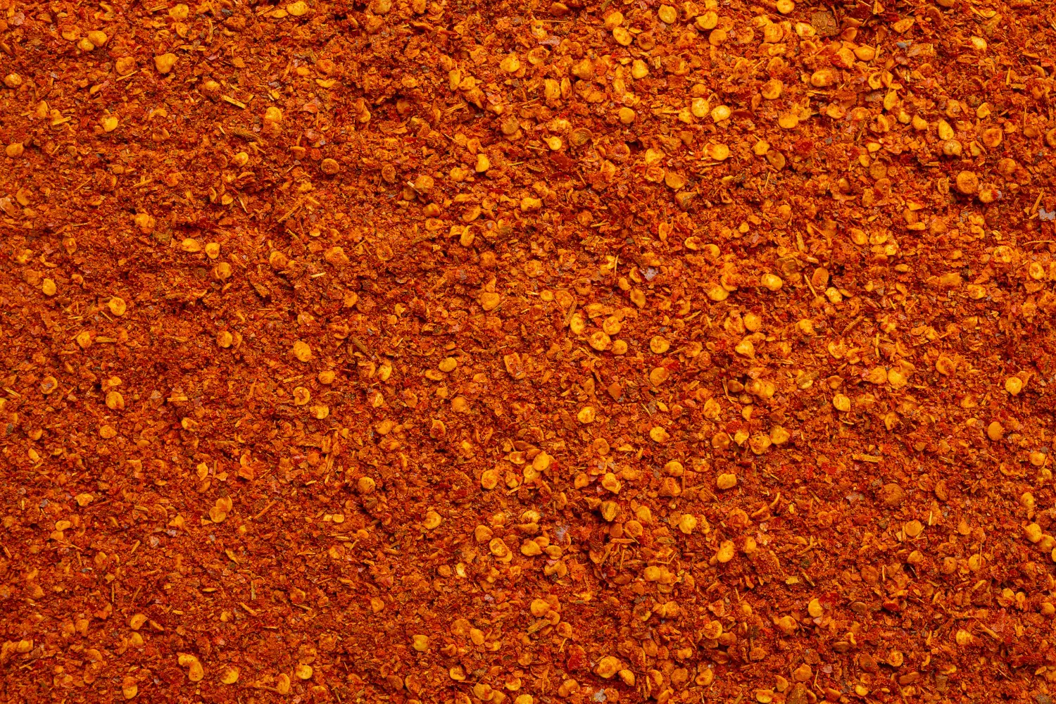 Full-frame image of coarse ground chorizo seasoning, with its vivid red color and speckled appearance.