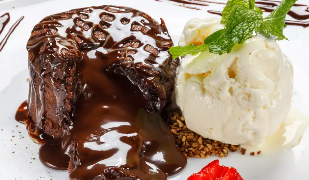 Cake filling ideas ,a luscious chocolate lava cake oozing with warm chocolate sauce, served with a scoop of vanilla ice cream, garnished with a fresh mint leaf, and a strawberry slice on the side.